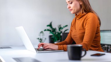 Genç, güzel, serbest çalışan bir kadın dizüstü bilgisayarla meşgul.