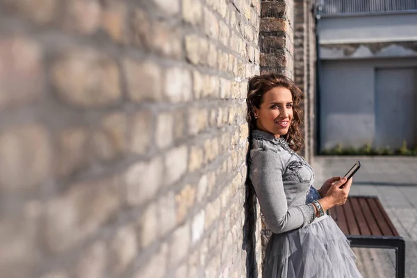 Leende kvinna håller tabletten och lutar mot väggen — Stockfoto