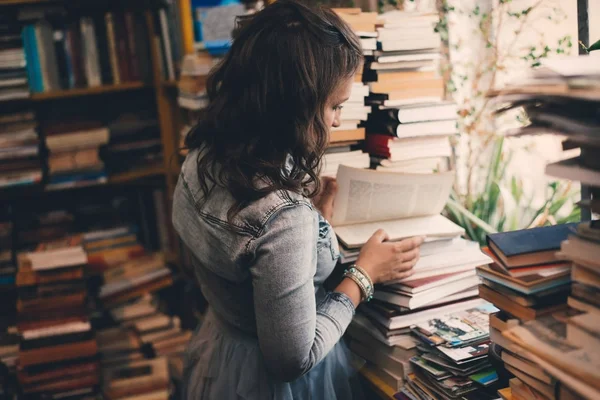 Μια όμορφη νεαρή γυναίκα στο βιβλιοπωλείο, ανοίγοντας ένα βιβλίο — Φωτογραφία Αρχείου
