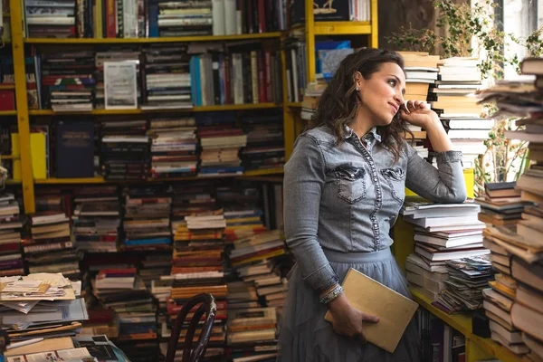 Στοχαστική γυναίκα ανάμεσα στα βιβλία στο βιβλιοπωλείο ή στη βιβλιοθήκη, — Φωτογραφία Αρχείου