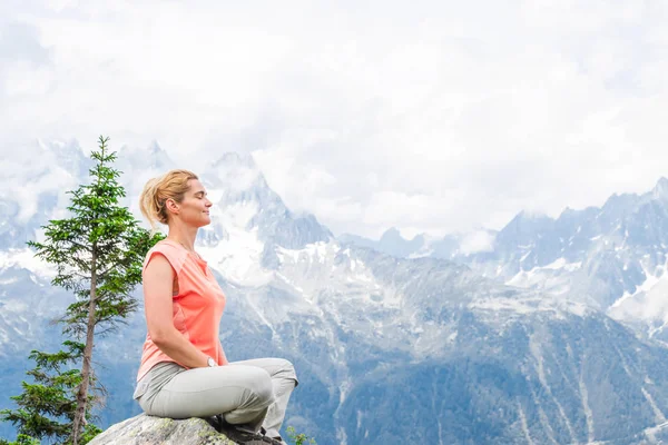 Female person enjoying peaceful meditation in the mountains