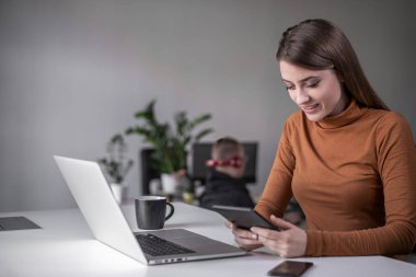 Genç ve güzel bir kadın ofiste teknolojik aletler kullanıyor.. 