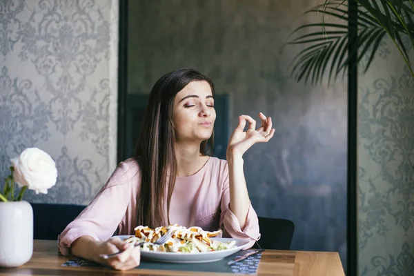 Genç bayan güzel bir restoranda oturuyor, öğle yemeğinin tadını çıkarıyor.