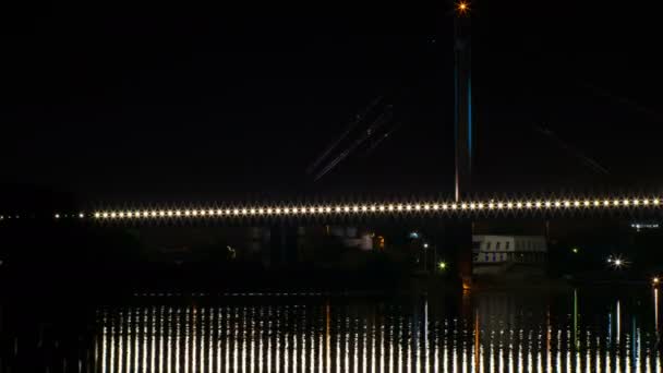 一条铁路桥梁在河上的夜间时间失效拍摄 灯光闪烁 反射在水面上 船通过 — 图库视频影像