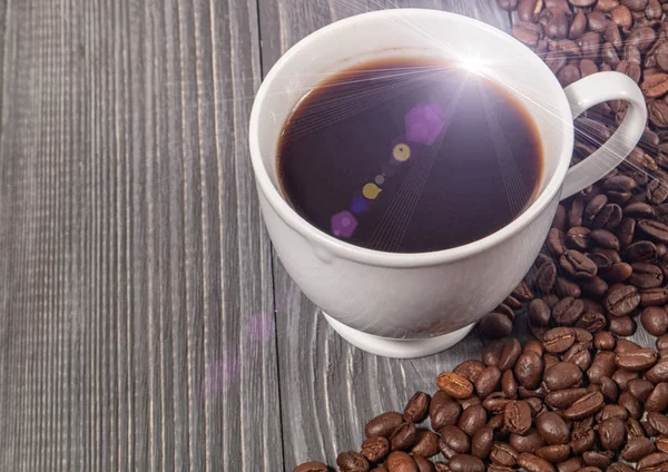 咖啡豆和一束美丽的光束在表面上一杯咖啡 — 图库照片