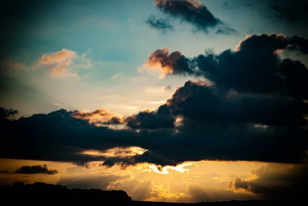 dark clouds against the evening sky and the rays of the setting sun