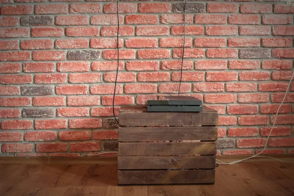 Game console on the vegetable box against the background of the inner wall of the room