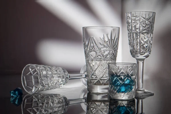 Crystal glasses on a mirror surface and a beautiful background painted with light