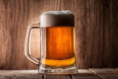 Bira ahşap arka plan üzerinde köpük bardak