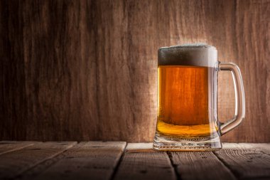 Bira ahşap arka plan üzerinde köpük bardak