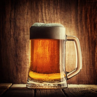 Bira ahşap arka plan üzerinde köpük bardak