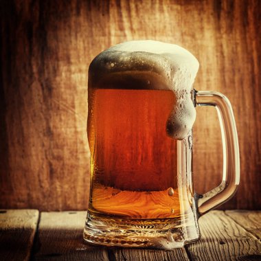 Bira ahşap arka plan üzerinde köpük bardak