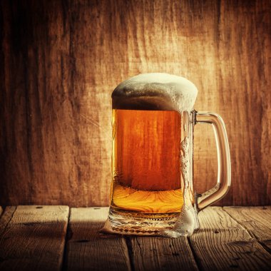 Bira ahşap arka plan üzerinde köpük bardak