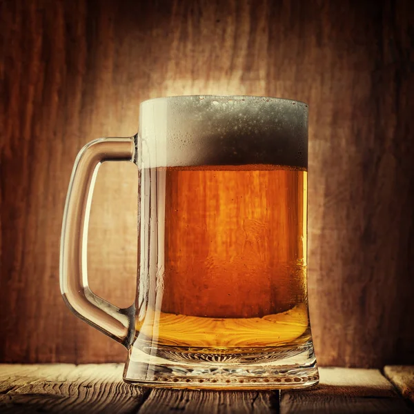 木製の背景上の泡とビールのジョッキ — ストック写真