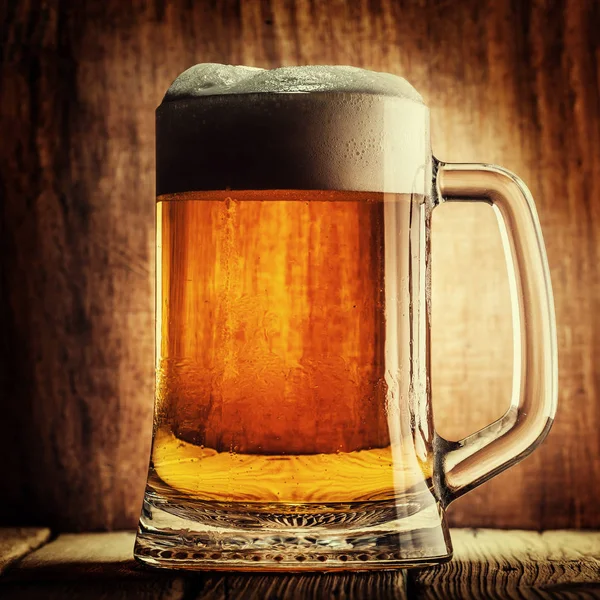 Bira ahşap arka plan üzerinde köpük bardak