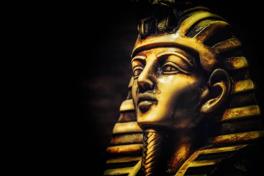 Stone pharaoh Tutankhamen mask on dark background clipart