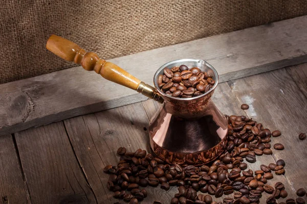 散落的咖啡豆和铜咖啡土耳其人在木质背景 — 图库照片
