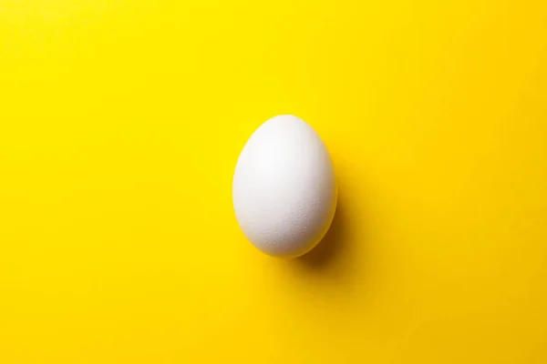 stock image white raw egg on yellow background, close up