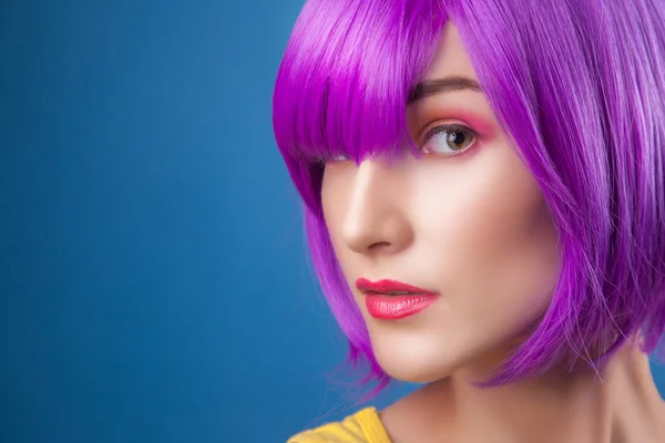 beautiful woman wearing colorful wig against blue background