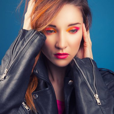 mavi arka plan üzerinde siyah deri ceketli güzel genç kadın