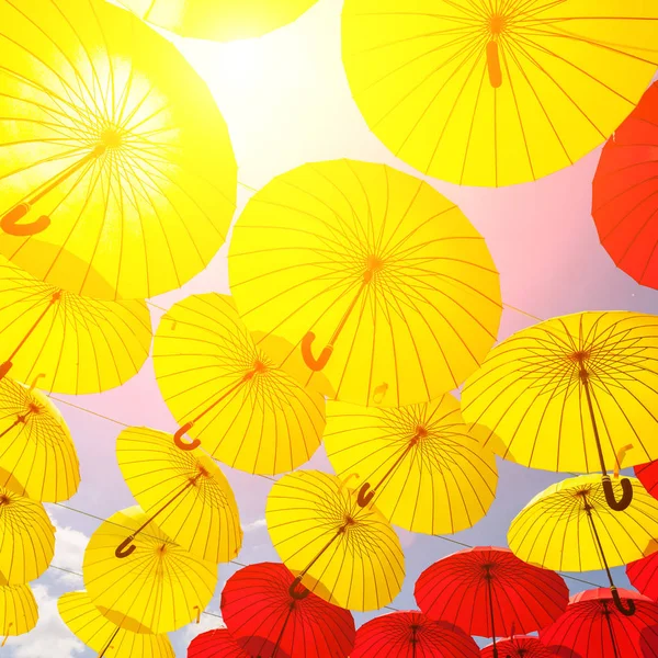 many yellow and red umbrellas against sky, street decoration