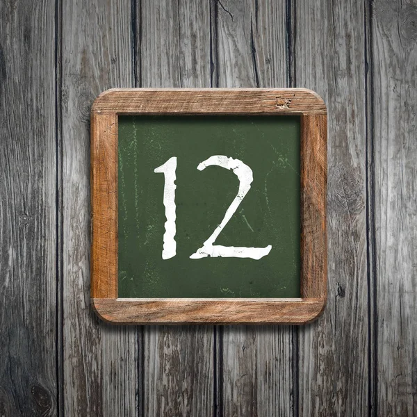 数字12在绿色黑板在木背景之上 — 图库照片