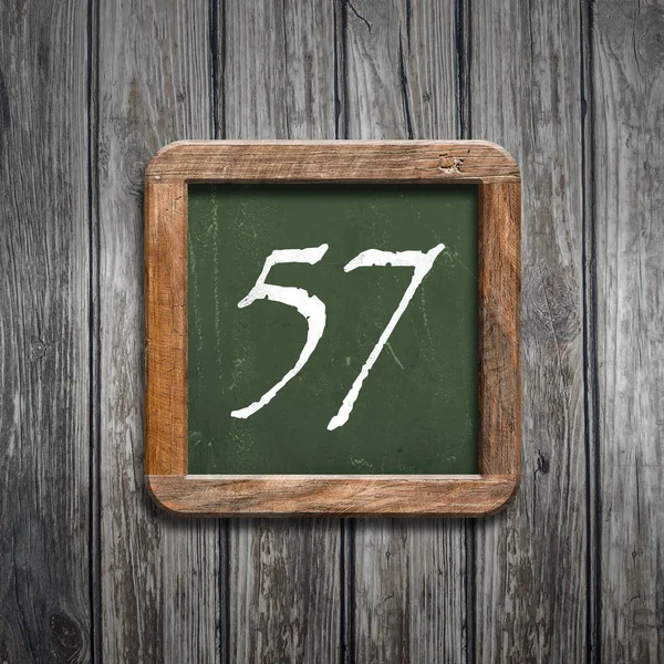 数字57在绿色黑板在木背景之上 — 图库照片