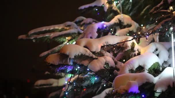 Vue rapprochée de l'arbre de Noël décoré de neige, de cadeaux et de guirlandes colorées 