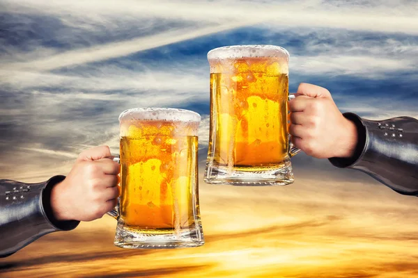 夕日を背景に新鮮なビールとマグカップを保持している男性 — ストック写真