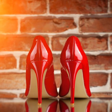 Kırmızı tuğla duvar arka plan üzerinde kırmızı yüksek topuklu