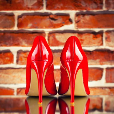 Kırmızı tuğla duvar arka plan üzerinde kırmızı yüksek topuklu