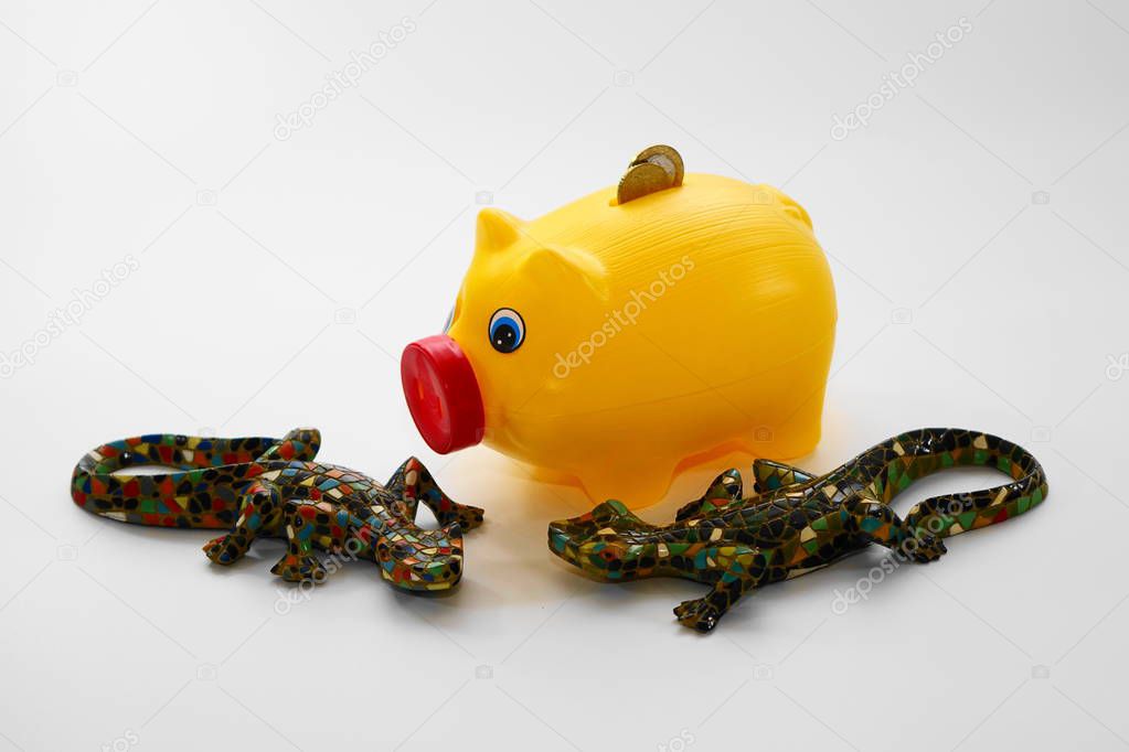 Yellow piggy bank and two reptiles Coins, money, pig and green mosaic reptile lizard crocodile.  Economies in danger.