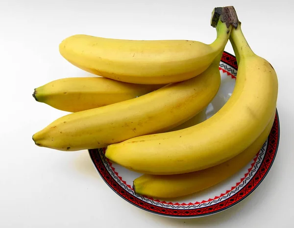 赤い余白の白い皿に5つの黄色いバナナ — ストック写真
