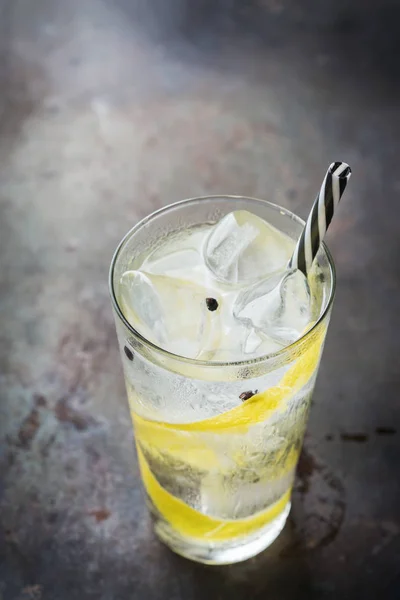 Food and drink, holidays party concept. Gin and tonic alcohol cocktail drink with ice and lemon zest in a glass on a grunge dark table.