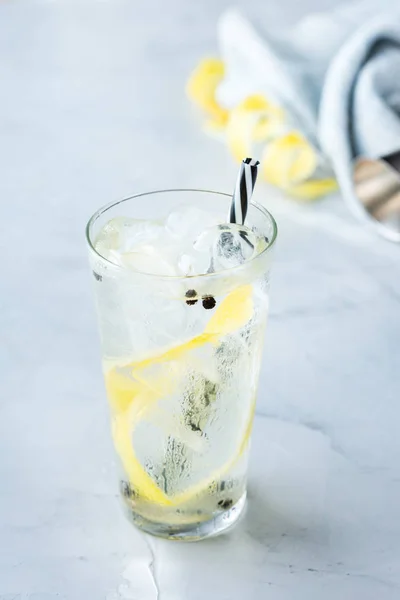 Food and drink, holidays party concept. Gin and tonic alcohol cocktail drink with ice and lemon zest in a glass on a table.