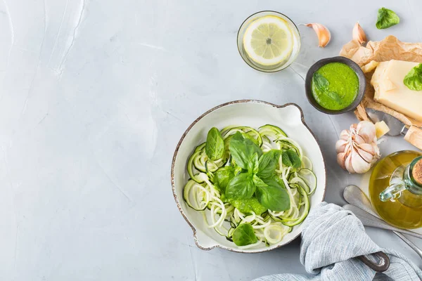 Food and drink, healthy eating and dieting concept. Seasonal fresh raw zucchini spaghetti pasta noodles with spinach pesto sauce and ingredients on the kitchen table. Top view flat lay background — Stock Image Food Drink Healthy Eating Dieting Concept Seasonal Fresh Raw Zucchini Stock Image
