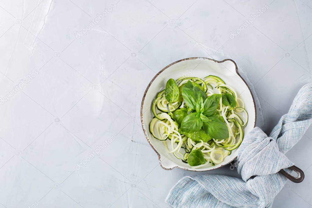 Food and drink, healthy eating and dieting concept. Seasonal fresh raw zucchini spaghetti pasta noodles with spinach pesto sauce on the kitchen table. Top view flat lay copy space background