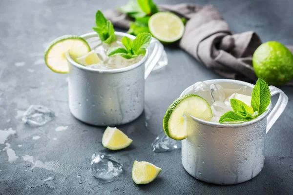 Food and drink, holidays party concept. Cold fresh classic beverage moscow mule cocktail in a silver mug with vodka, ginger beer. lime and mint for refreshment in summer days