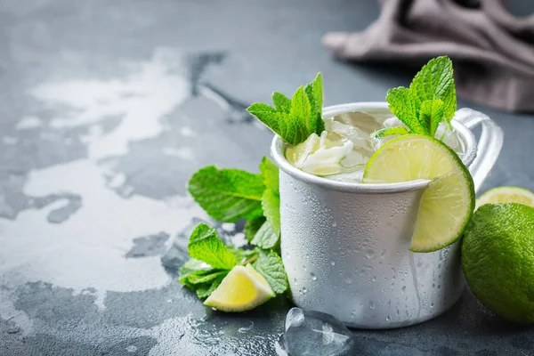 Food and drink, holidays party concept. Cold fresh classic beverage moscow mule cocktail in a silver mug with vodka, ginger beer. lime and mint for refreshment in summer days. Copy space background