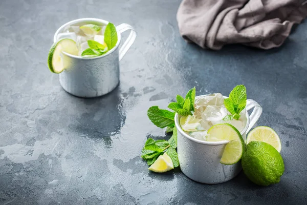 Food and drink, holidays party concept. Cold fresh classic beverage moscow mule cocktail in a silver mug with vodka, ginger beer. lime and mint for refreshment in summer days