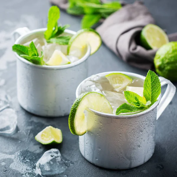 Food and drink, holidays party concept. Cold fresh classic beverage moscow mule cocktail in a silver mug with vodka, ginger beer. lime and mint for refreshment in summer days