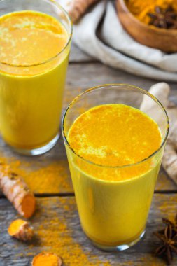 Geleneksel Hint içki zerdeçal altın süt bir cam malzemeler, zencefil, curcuma, rustik ahşap bir masa üzerinde bal ile