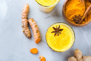 Bir cam malzemeler, zencefil, curcuma, mutfak masası bal ile geleneksel Hint içki zerdeçal altın süt. Üst görüntülemek düz yatıyordu arka plan