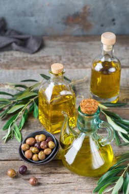 Gıda diyet ve beslenme kavramı. Taze organik sızma zeytinyağı şişeleri rustik ahşap bir masa üzerinde yeşil yaprakları ile ürün yelpazesine
