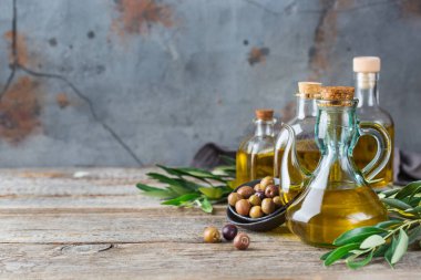 Gıda diyet ve beslenme kavramı. Taze organik sızma zeytinyağı şişeleri rustik ahşap bir masa üzerinde yeşil yaprakları ile ürün yelpazesine. Alan arka plan kopyalama