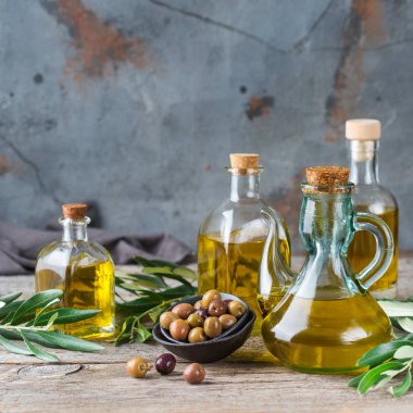Gıda diyet ve beslenme kavramı. Taze organik sızma zeytinyağı şişeleri rustik ahşap bir masa üzerinde yeşil yaprakları ile ürün yelpazesine