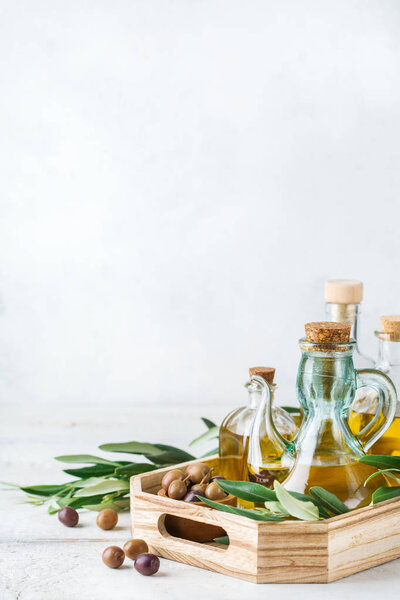 Концепция питания и питания. Ассортимент свежего органического оливкового масла высшего сорта в бутылках с зелеными листьями на деревенском деревянном столе. Копирование белого фона
