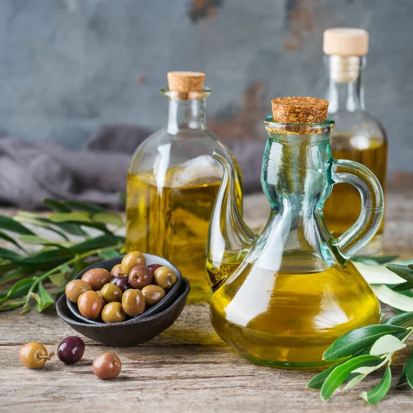 Gıda diyet ve beslenme kavramı. Taze organik sızma zeytinyağı şişeleri rustik ahşap bir masa üzerinde yeşil yaprakları ile ürün yelpazesine