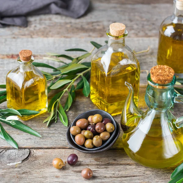Gıda diyet ve beslenme kavramı. Taze organik sızma zeytinyağı şişeleri rustik ahşap bir masa üzerinde yeşil yaprakları ile ürün yelpazesine