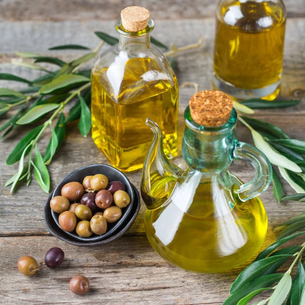 Gıda diyet ve beslenme kavramı. Taze organik sızma zeytinyağı şişeleri rustik ahşap bir masa üzerinde yeşil yaprakları ile ürün yelpazesine